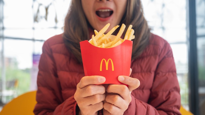 A woman holding McDonald's french fries before eating in McDonald's restaurant.