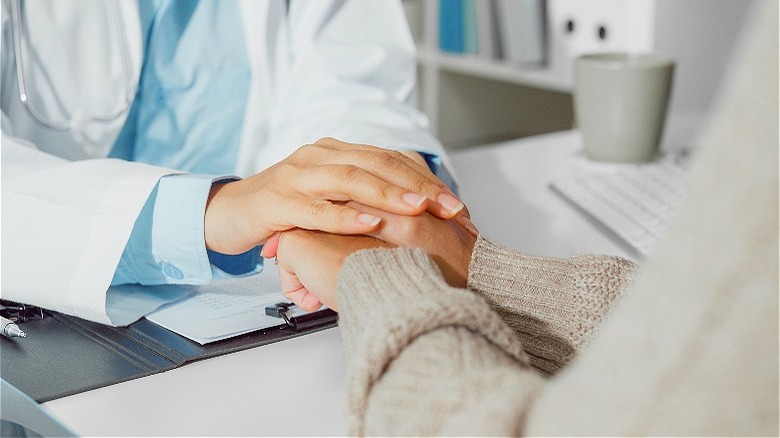 Doctor clasps person's hands