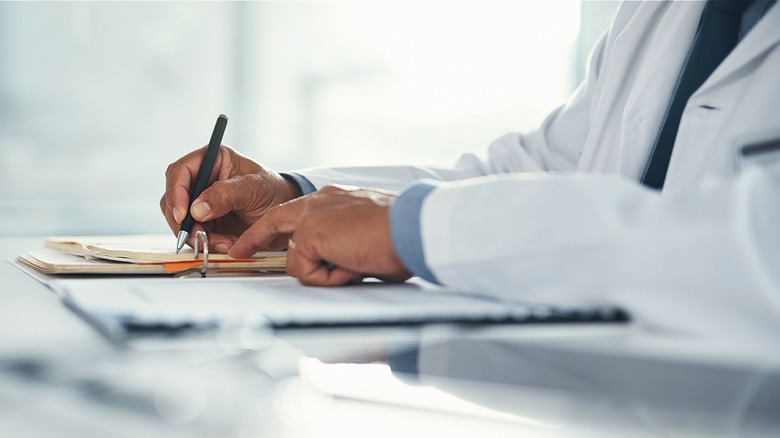 Doctor fills out paperwork