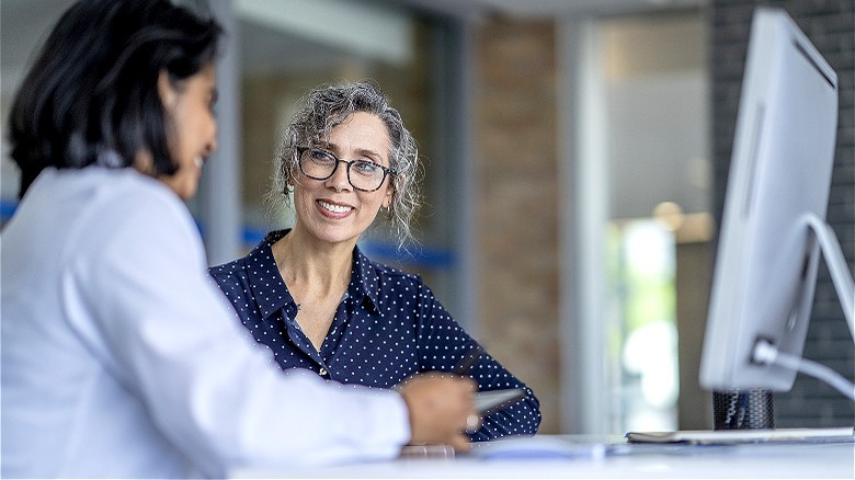 Person smiling, confers with doctor