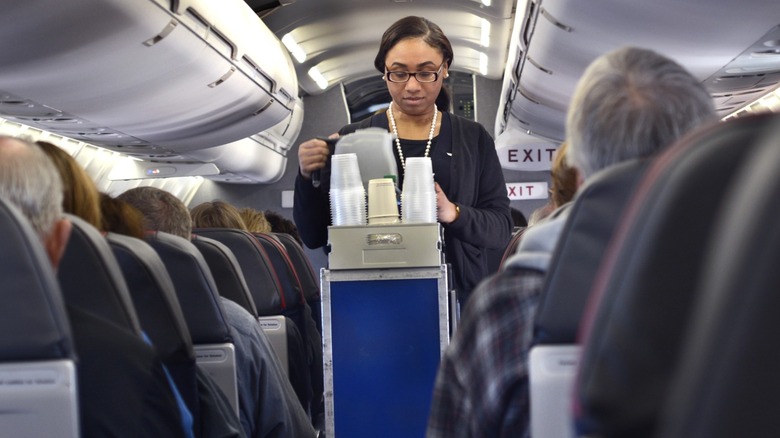 an American Airlines flight attendant serves drinks in an airplane cabin
