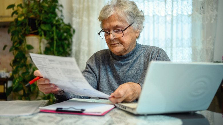Older lady sitting at table looking over bills