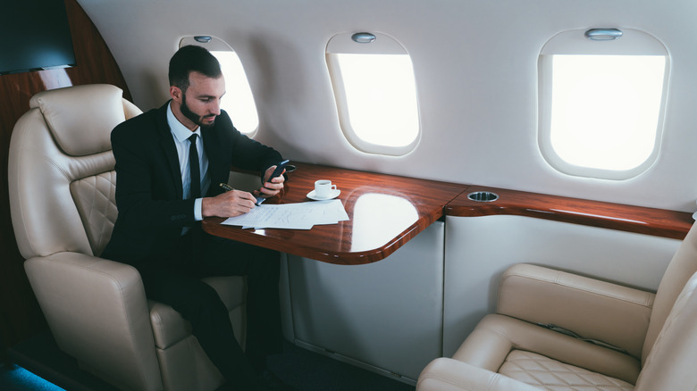 Man in formal business attire on a private plane doing work