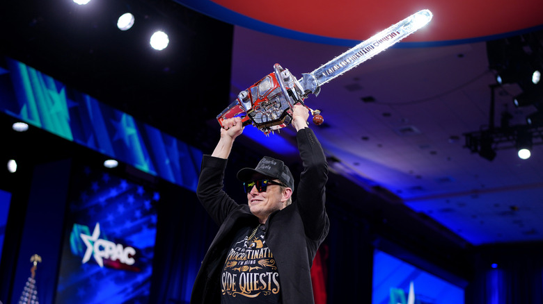 Elon Musk wields a chainsaw over his head at CPAC.