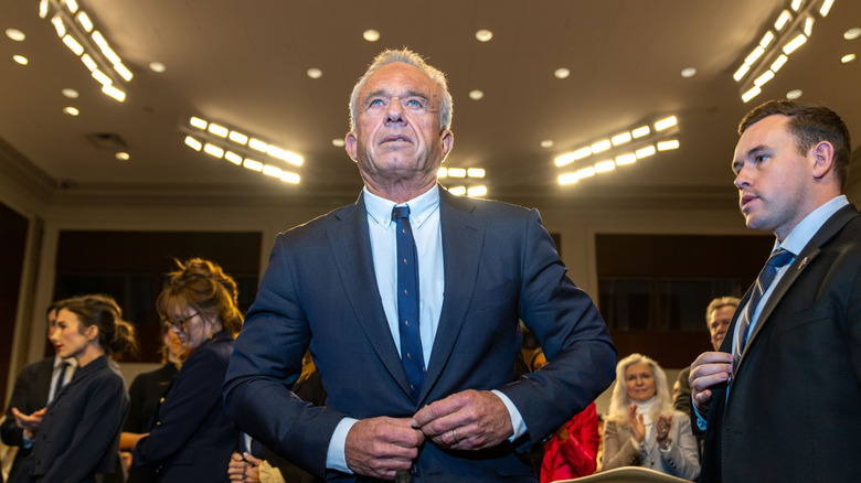Robert F Kennedy Jr standing and buttoning his suit jacket