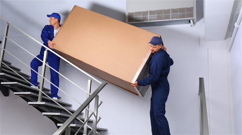 Movers moving box up stairs