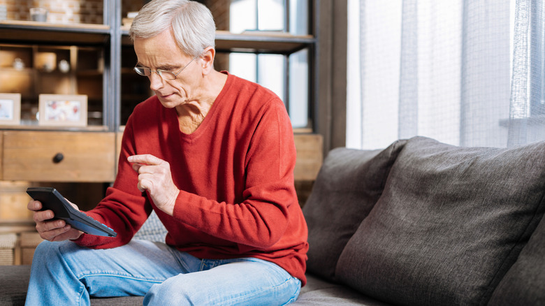Older man in red shirt using calculator