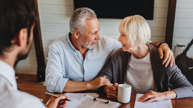 Happy older couple reviewing paperwork with a younger man