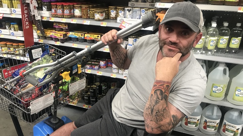 Russel Hantz holding crutches in a grocery store aisle