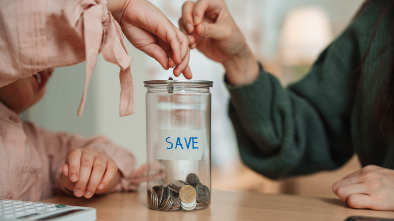 Hands placing coins into savings jar