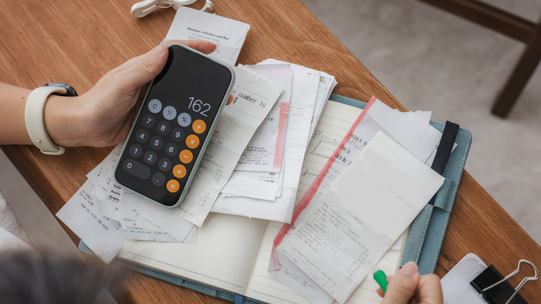 Person using calculator to pay bills and consider investments