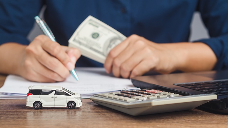 person with money signing paperwork
