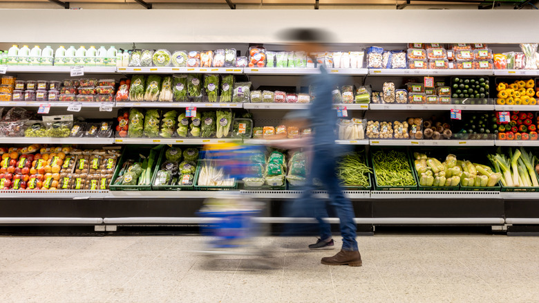 Person pushing shopping cart inside grocery store