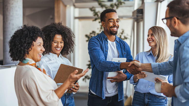 Professionals smiling and shaking hands, illustrating human interaction.