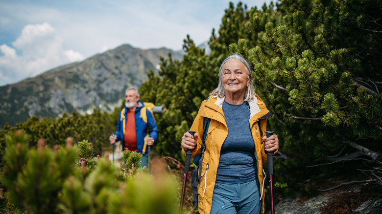 A senior man and smiling senior woman hiking on a mountain trail