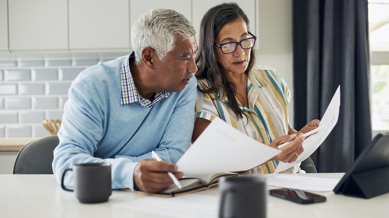 A senior couple at a table in the kitchen discussing documents
