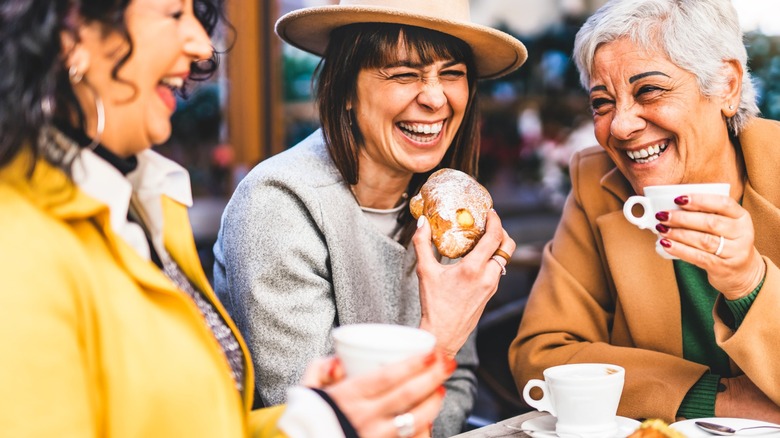 Group of senior women enjoying pastries and beverages at an outdoor eatery