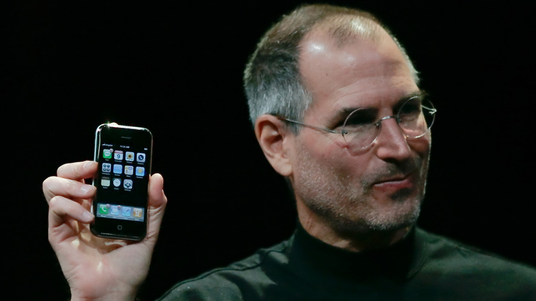 Steve Jobs holding the original Apple iPhone