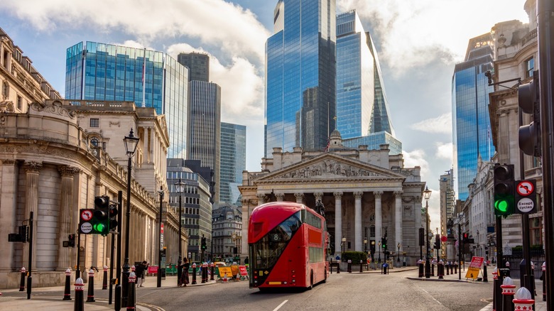 A red bus driving in front of London's Royal Exchange building near the city's financial district.