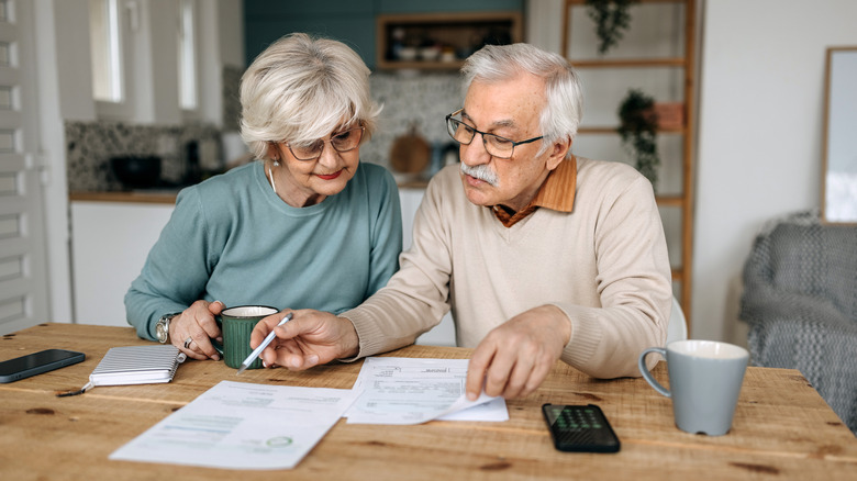 A senior couple sitting at a dining room table while looking over documents