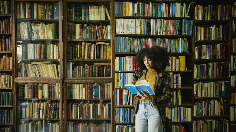 woman reading a book in a large home library
