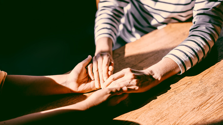 two people holding hands depicting support after a loss