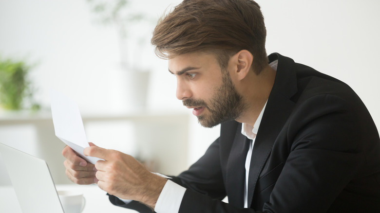 A person in suit feeling shocked while reading a letter