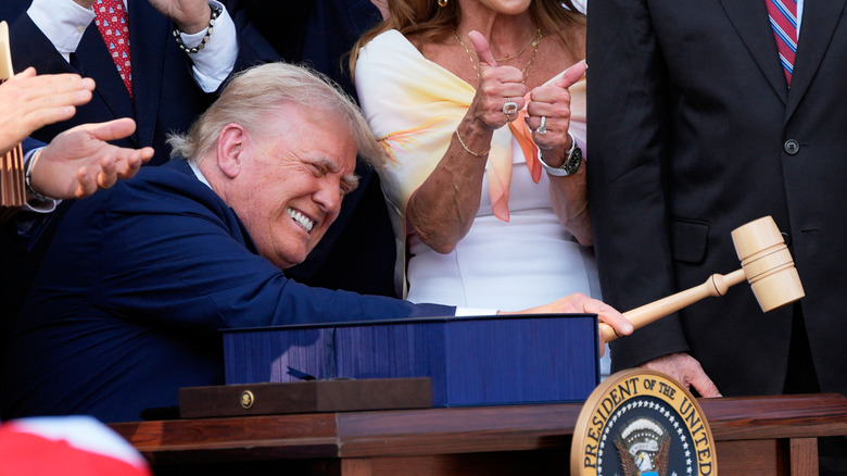 Donald Trump grimacing as he swings a gavel after signing the One Big Beautiful Bill Act
