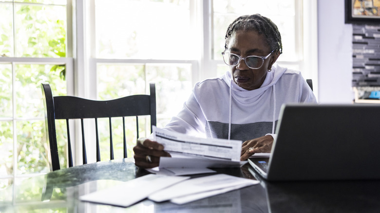 A mature woman looking over paperwork while seated at table