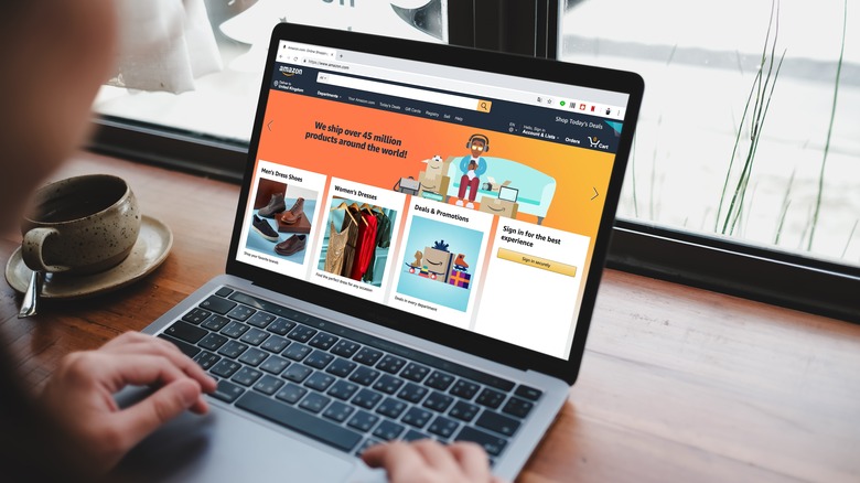 A woman typing a laptop displaying the Amazon website