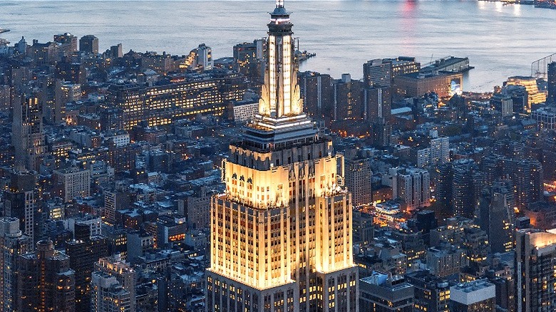 The top of the Empire State Building illuminated at night, over the twilit city