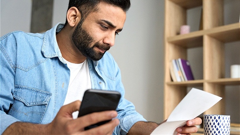 Person reviewing letter, holding phone