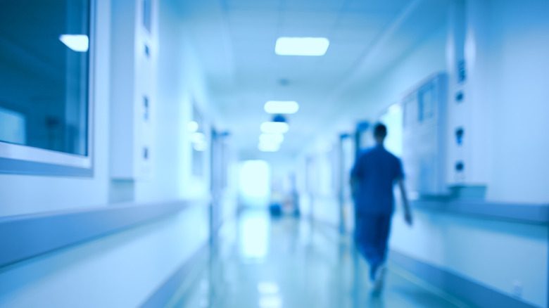 A stylistically blurred, blue-toned hospital corridor, depicting drama and unease in healthcare.
