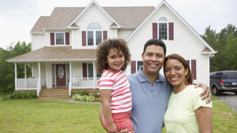 A happy family standing in front of their average home