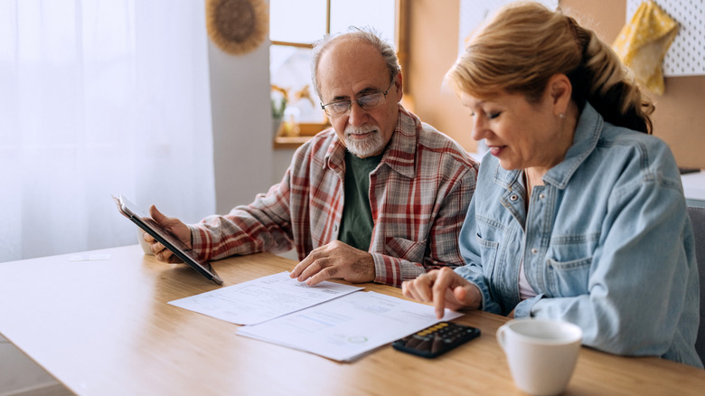 A mature couple with a calculator reviewing dosuments