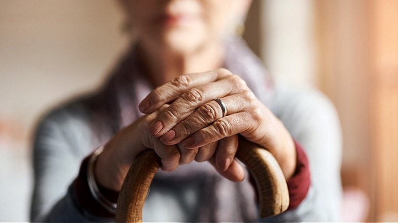 Close-up hands folded around cane