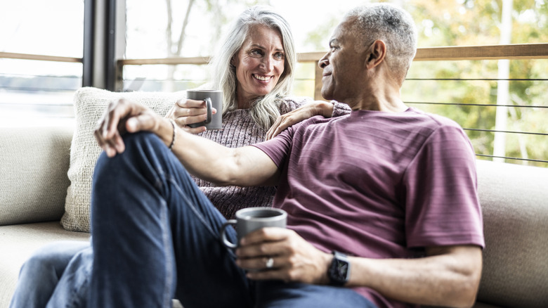 Senior couple having coffee and embracing on back porch of vacation home