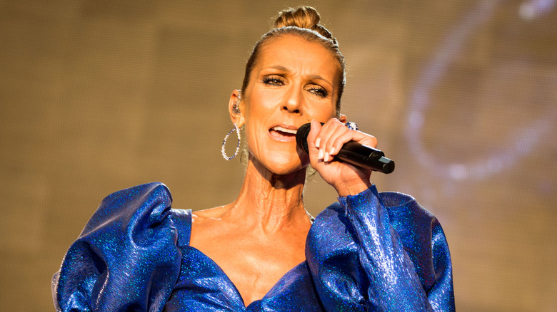 Celine Dion holding a microphone and singing onstage.