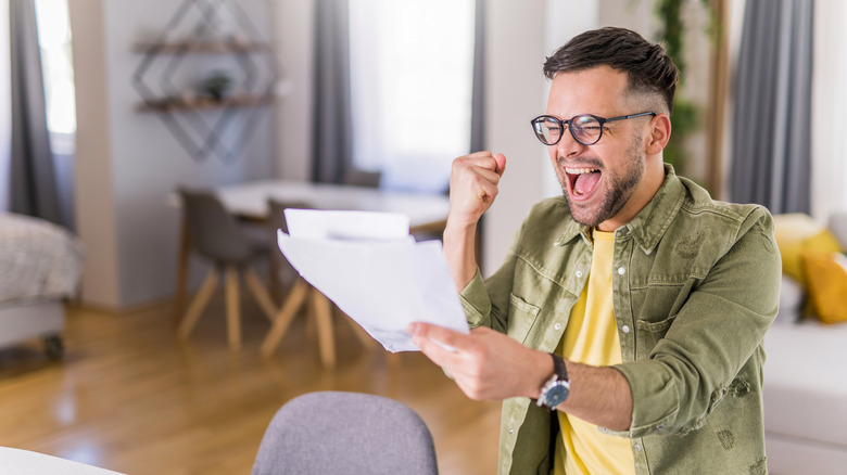 Person reading paperwork, exclaiming joy