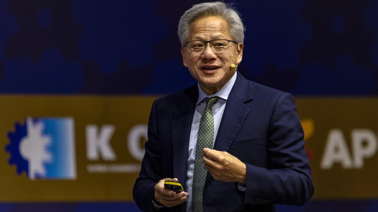 Nvidia CEO, Jensen Huang, holding a device while on stage giving a speech.