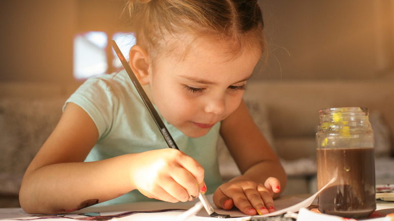 Small girl painting on a table at home