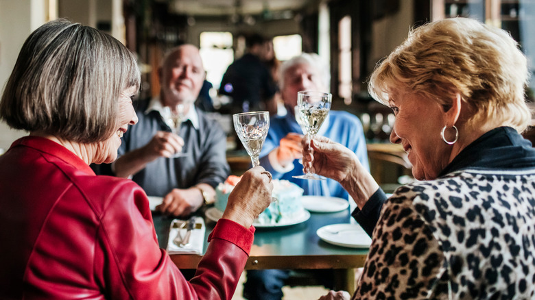 A group of mature friends sitting at a table in a restaurant celebrating a birthday