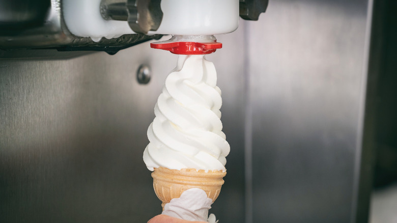 A soft serve ice cream cone being dispensed from machine