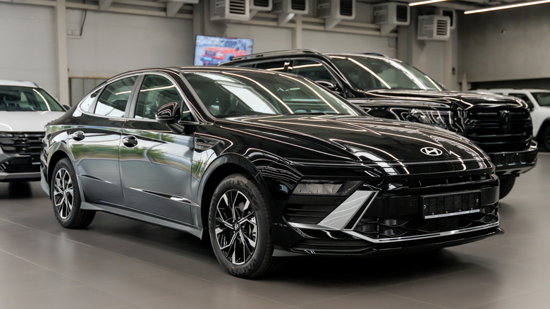 A dark-colored Hyundai Sonata parked next to other models in a dealership