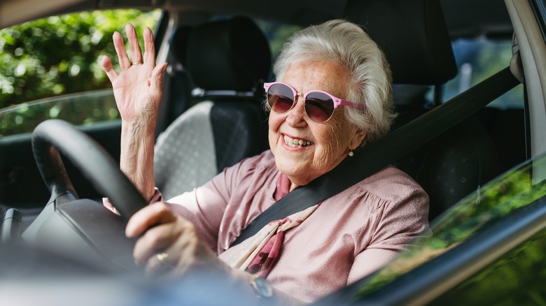Happy older woman with sunglasses driving car