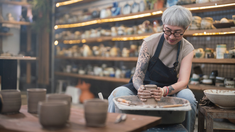 Older woman making pottery in studio