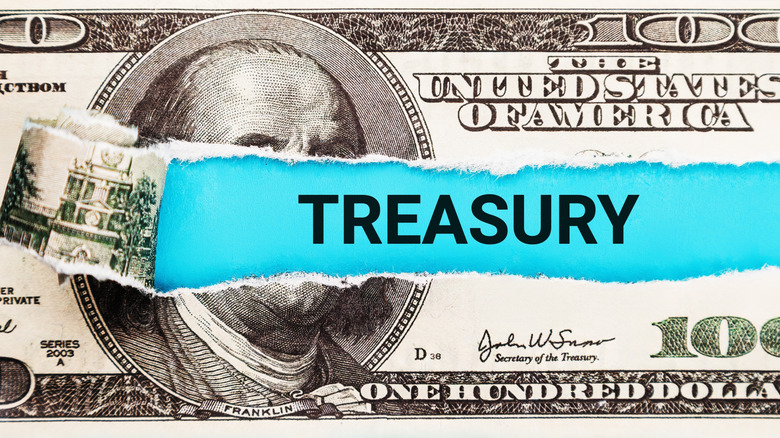 A ripped $100 bill with treasury written in the middle