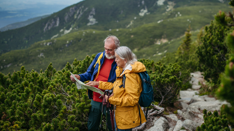 Senior man and woman reading map during a mountain hike
