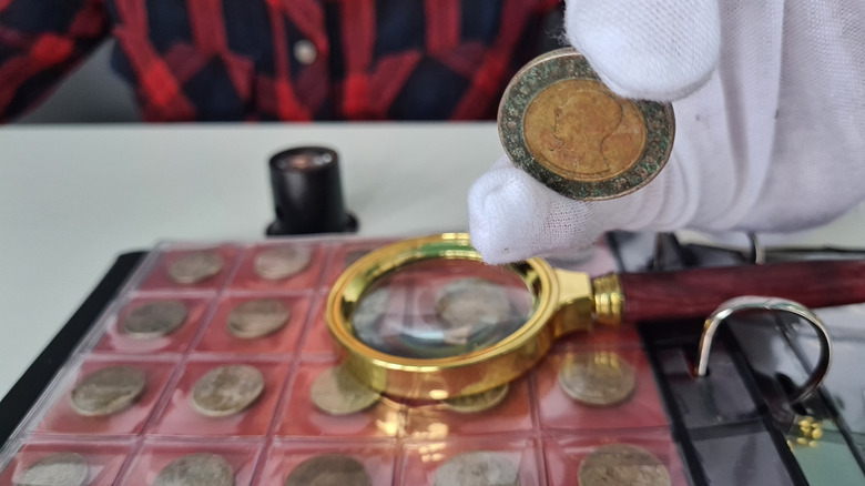 examining a rare coin on table