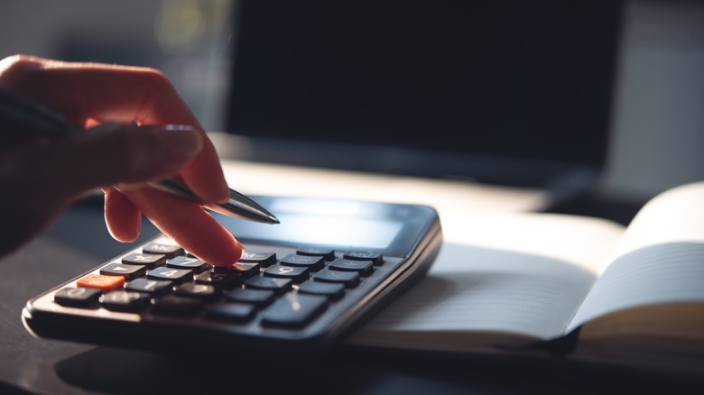 Person calculating a budget on calculator.